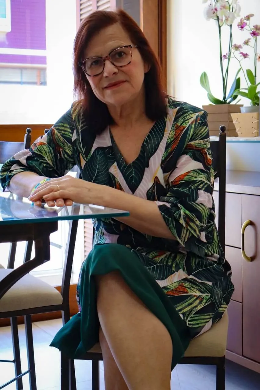 Neuza Leal sentada em ambiente claro